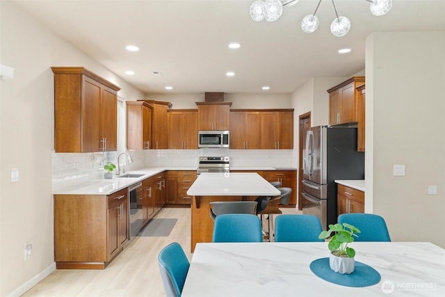 kitchen featuring stainless steel appliances, a kitchen island, brown cabinets, light wood-style flooring, and recessed lighting