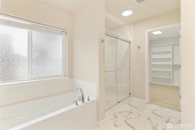 bathroom with marble finish flooring, a shower stall, a bath, and a spacious closet