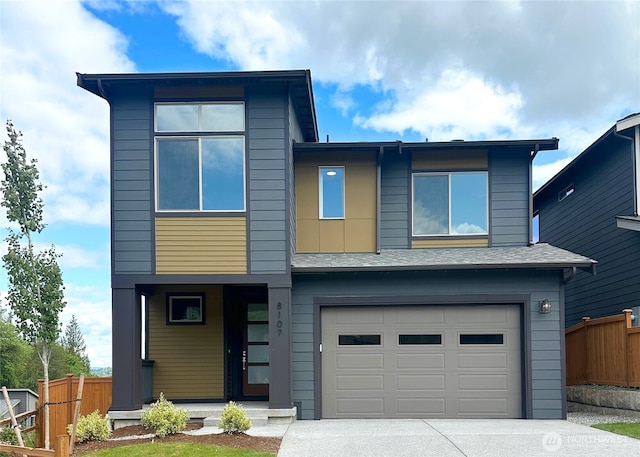view of front of home featuring fence, concrete driveway, and a garage