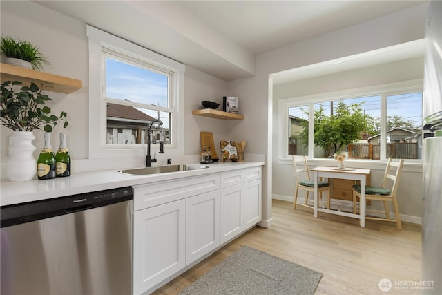 kitchen featuring stainless steel dishwasher, open shelves, a sink, white cabinets, and light wood-style floors