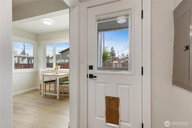 entryway with light wood-style floors, baseboards, and electric panel