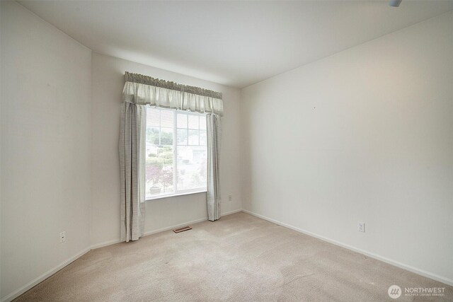 spare room with light carpet and baseboards