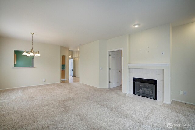 unfurnished living room featuring carpet, a tile fireplace, a chandelier, and baseboards