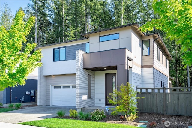 modern home with a garage, fence, a balcony, and concrete driveway