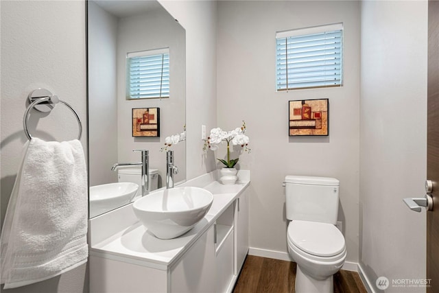 bathroom featuring wood finished floors, toilet, vanity, and baseboards