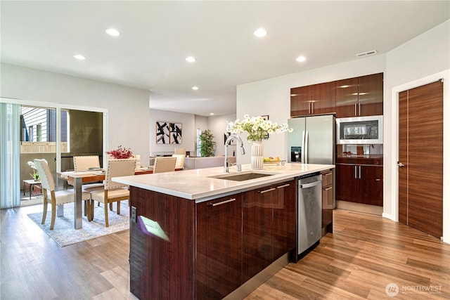 kitchen featuring a sink, appliances with stainless steel finishes, light wood-style floors, light countertops, and recessed lighting