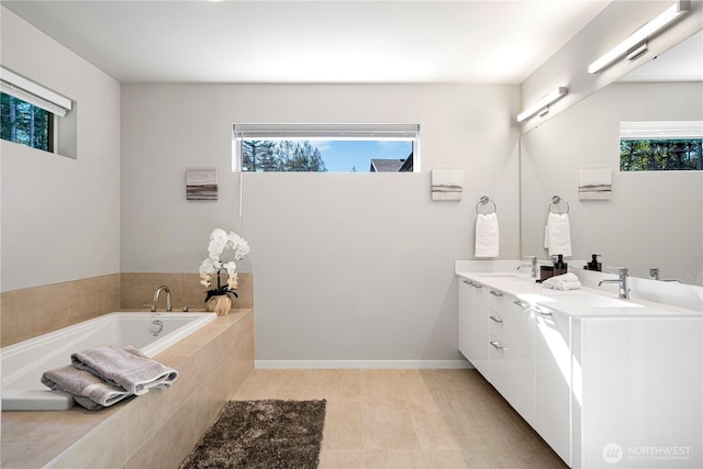 full bath with a bath, double vanity, and baseboards
