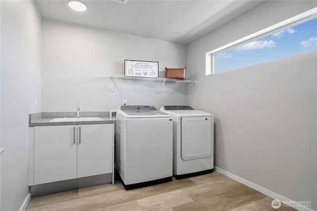 laundry room with independent washer and dryer, light wood-type flooring, cabinet space, and baseboards
