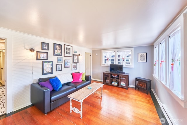 1214 Bay Ave, Ocean Park, WA 98640 - living room with a wood stove, wood finished floors, baseboard heating, baseboards, and crown molding