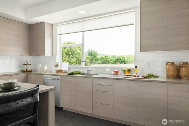 kitchen featuring modern cabinets, a sink, backsplash, and dishwasher