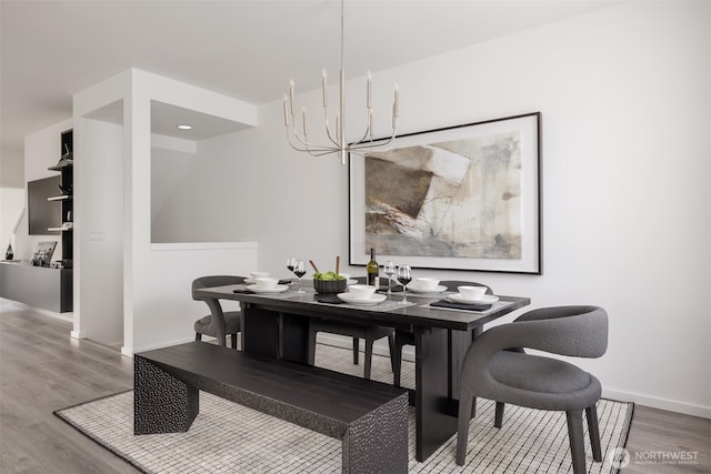 dining area with a chandelier, wood finished floors, and baseboards