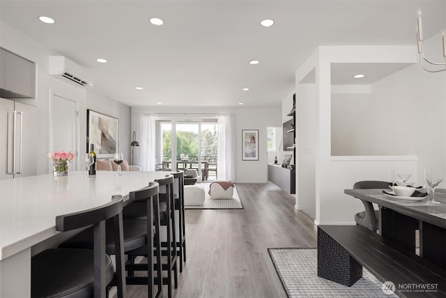 dining area featuring an AC wall unit, recessed lighting, light wood-style flooring, and baseboards