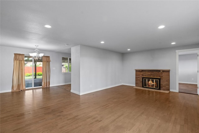 unfurnished living room with a chandelier, recessed lighting, baseboards, wood finished floors, and a fireplace