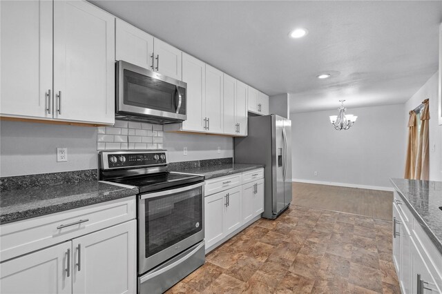 kitchen featuring appliances with stainless steel finishes, stone finish floors, a chandelier, white cabinetry, and recessed lighting