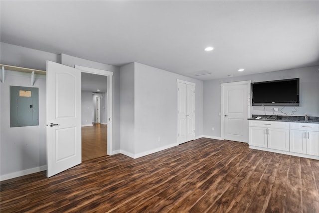 unfurnished living room featuring electric panel, dark wood-style floors, baseboards, and recessed lighting