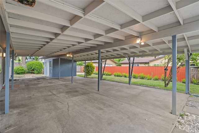 view of car parking with fence and a storage shed