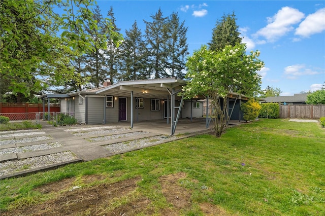 rear view of property featuring an attached carport, a patio, driveway, and a chimney