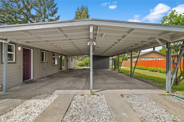 view of vehicle parking with an attached carport, fence, and driveway