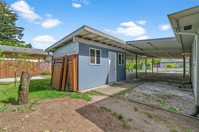 view of outbuilding with fence and an attached carport