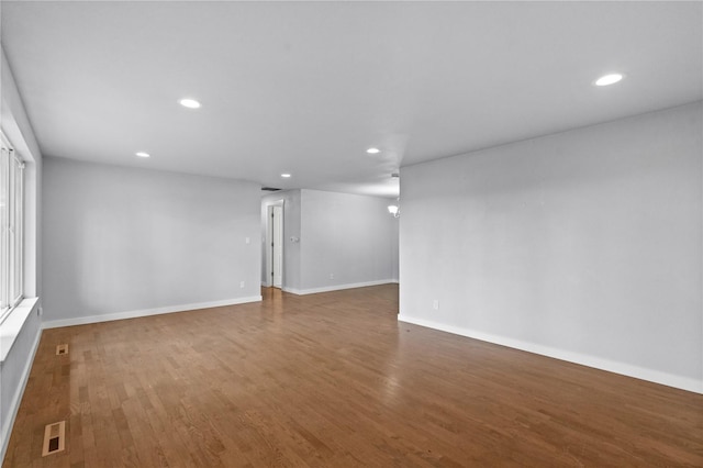 unfurnished room featuring recessed lighting, wood finished floors, and baseboards
