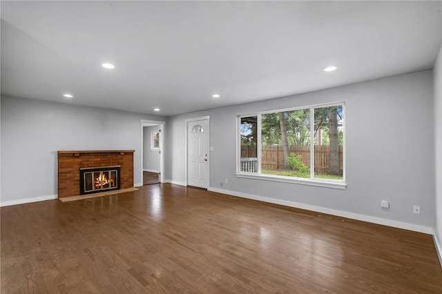 unfurnished living room featuring recessed lighting, baseboards, wood finished floors, and a fireplace