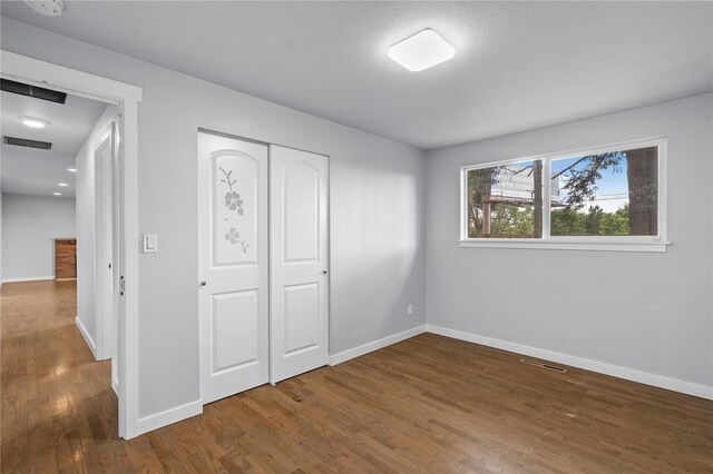unfurnished bedroom featuring wood finished floors, baseboards, and a closet