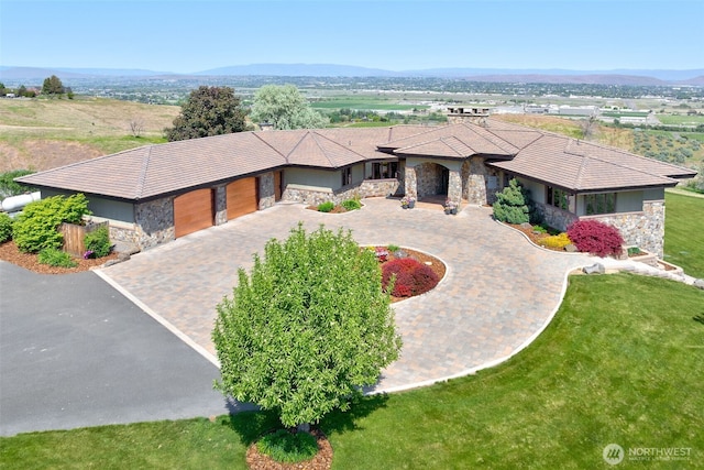 1041 Red Sky Dr, Yakima, WA 98903 - prairie-style house with stone siding, curved driveway, an attached garage, a tiled roof, and a mountain view