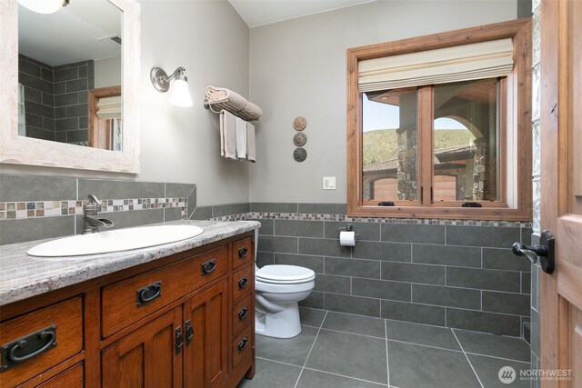 1041 Red Sky Dr, Yakima, WA 98903 - bathroom with tile patterned flooring, tile walls, toilet, vanity, and wainscoting
