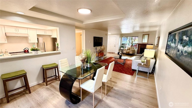 8407 18th Ave W Unit 4-102, Everett, WA 98204 - dining area featuring a raised ceiling, light wood-style floors, baseboards, and a textured ceiling