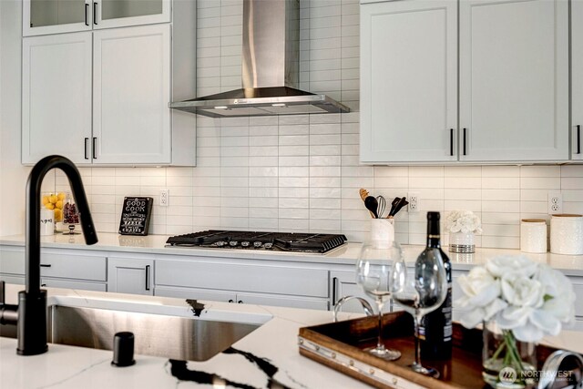 16215 Simonds Rd NE Unit 3, Kenmore, WA 98028 - kitchen with wall chimney exhaust hood, stainless steel gas cooktop, a sink, decorative backsplash, and glass insert cabinets