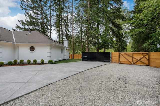 12805 Ruggs Lake Rd, Everett, WA 98208 - view of property exterior with a gate, a chimney, fence, concrete driveway, and stucco siding