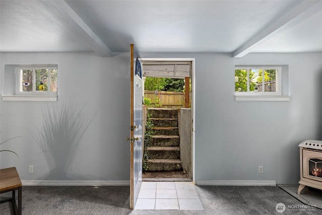 entryway featuring a wood stove, beamed ceiling, carpet flooring, and baseboards