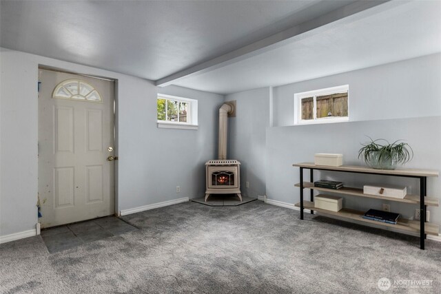 entryway with carpet flooring, a wood stove, beamed ceiling, baseboards, and heating unit