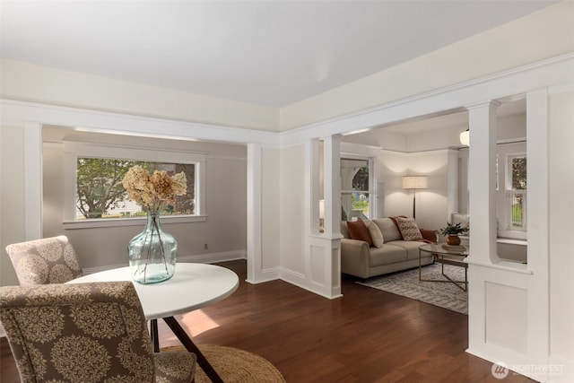 sitting room featuring decorative columns, dark wood-type flooring, and healthy amount of natural light
