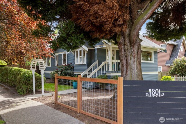 view of property hidden behind natural elements featuring a fenced front yard and a gate