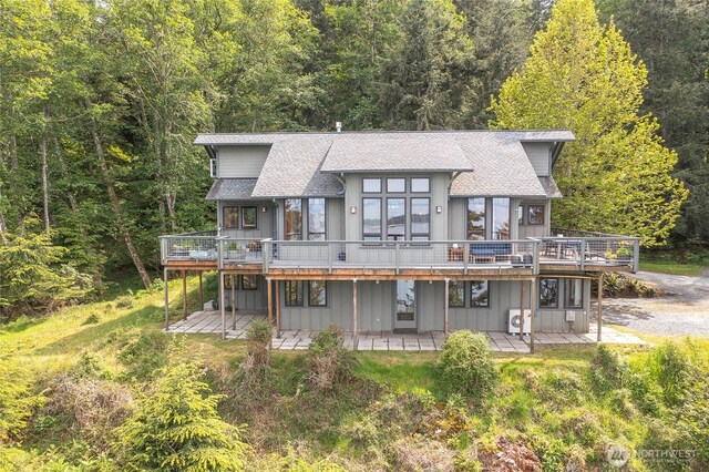 91 Coastline Dr, Orcas Island, WA 98279 - rear view of property featuring a wooden deck, a forest view, a shingled roof, and board and batten siding