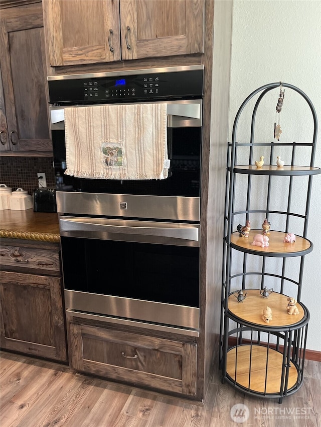137 La Due Cemetery Rd, Onalaska, WA 98570 - kitchen featuring stainless steel double oven, dark countertops, light wood-style floors, dark brown cabinets, and backsplash