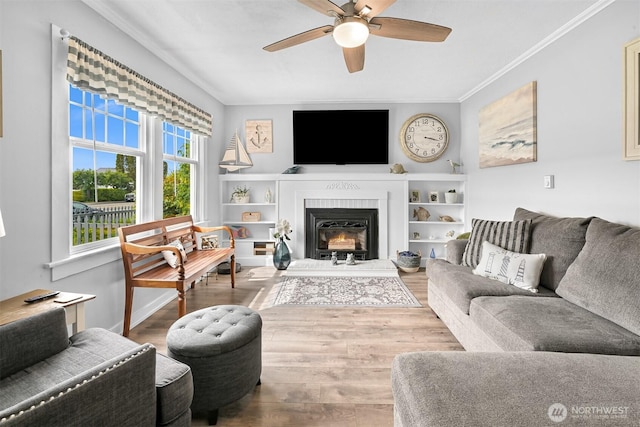 1060 Peace Portal Dr, Blaine, WA 98230 - living room featuring a ceiling fan, wood finished floors, ornamental molding, and a warm lit fireplace