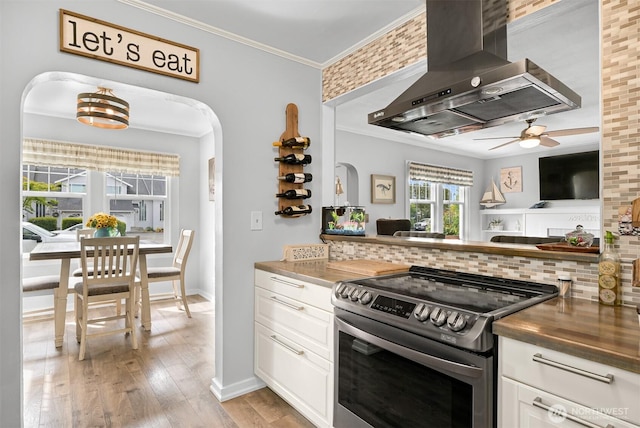 1060 Peace Portal Dr, Blaine, WA 98230 - kitchen with stainless steel electric range oven, wall chimney range hood, tasteful backsplash, crown molding, and ceiling fan