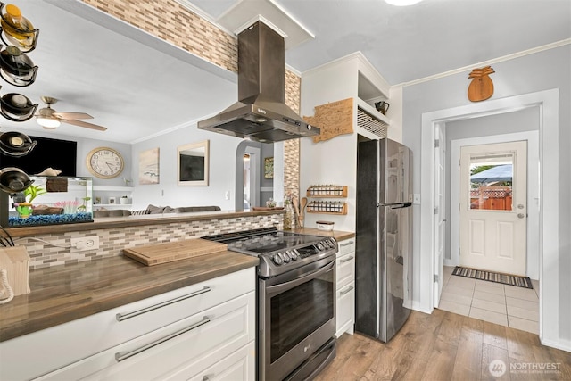 1060 Peace Portal Dr, Blaine, WA 98230 - kitchen featuring appliances with stainless steel finishes, ventilation hood, wood counters, light wood-style floors, and white cabinetry