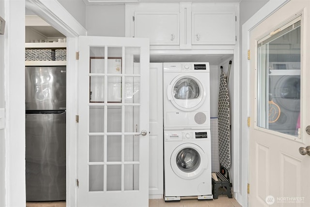 1060 Peace Portal Dr, Blaine, WA 98230 - laundry room with stacked washing machine and dryer, cabinet space, and light tile patterned floors