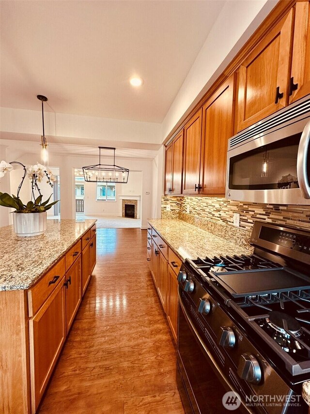 4660 NE 3rd Ct Unit J3, Renton, WA 98059 - kitchen featuring range with gas stovetop, stainless steel microwave, light stone countertops, tasteful backsplash, and wood finished floors
