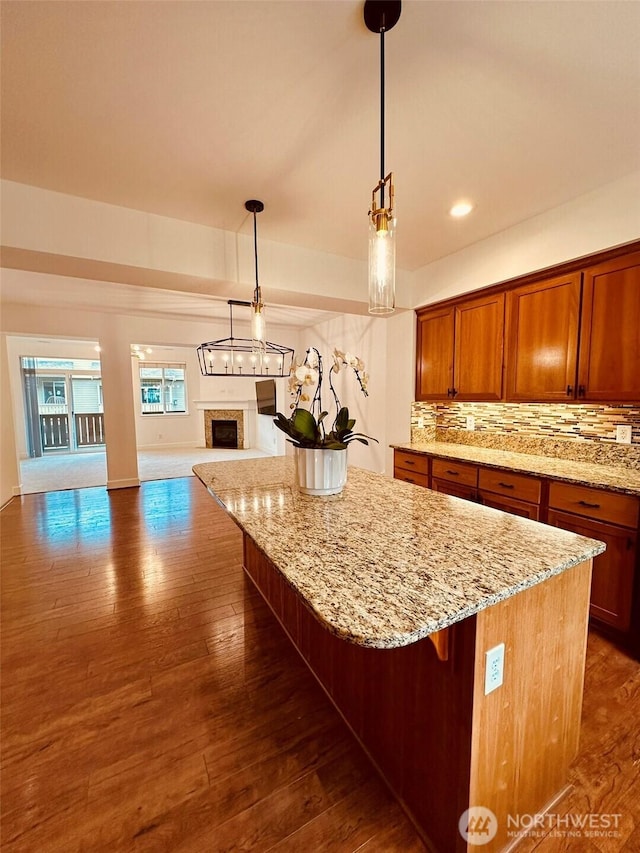 4660 NE 3rd Ct Unit J3, Renton, WA 98059 - kitchen with open floor plan, a center island, backsplash, light stone counters, and dark wood-type flooring
