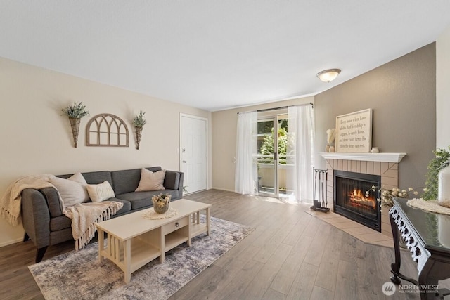 living area with a fireplace, wood finished floors, and baseboards