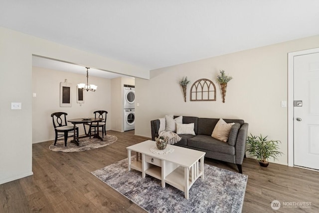 living area featuring estacked washer and dryer, wood finished floors, and a chandelier