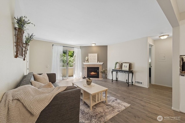 living area with wood finished floors, a fireplace with flush hearth, and baseboards