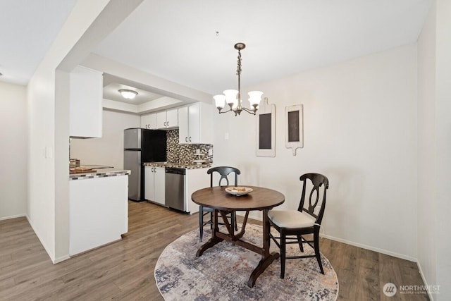 dining area featuring a chandelier, wood finished floors, and baseboards