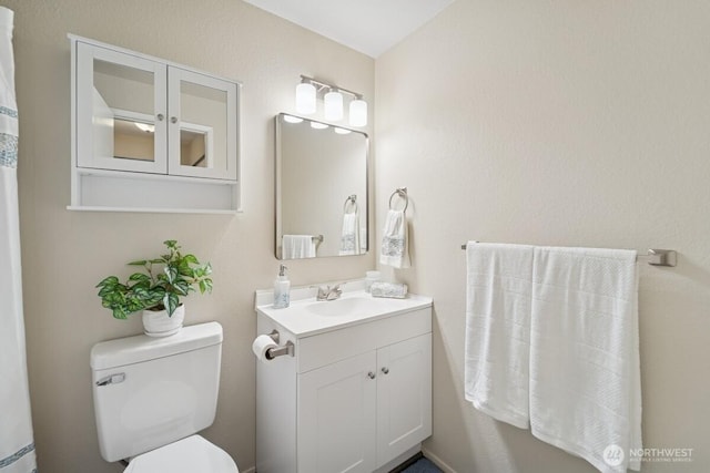 bathroom with toilet, vanity, and baseboard heating