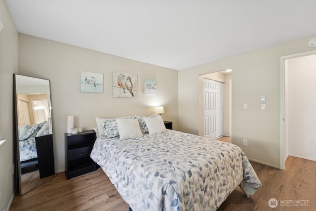 bedroom with wood finished floors, a closet, and baseboards