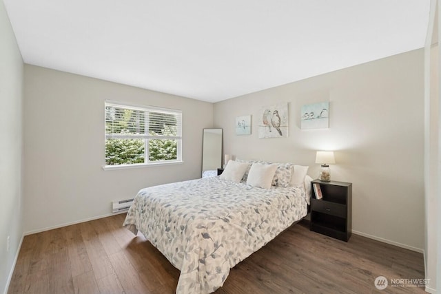 bedroom with a baseboard radiator, wood finished floors, and baseboards